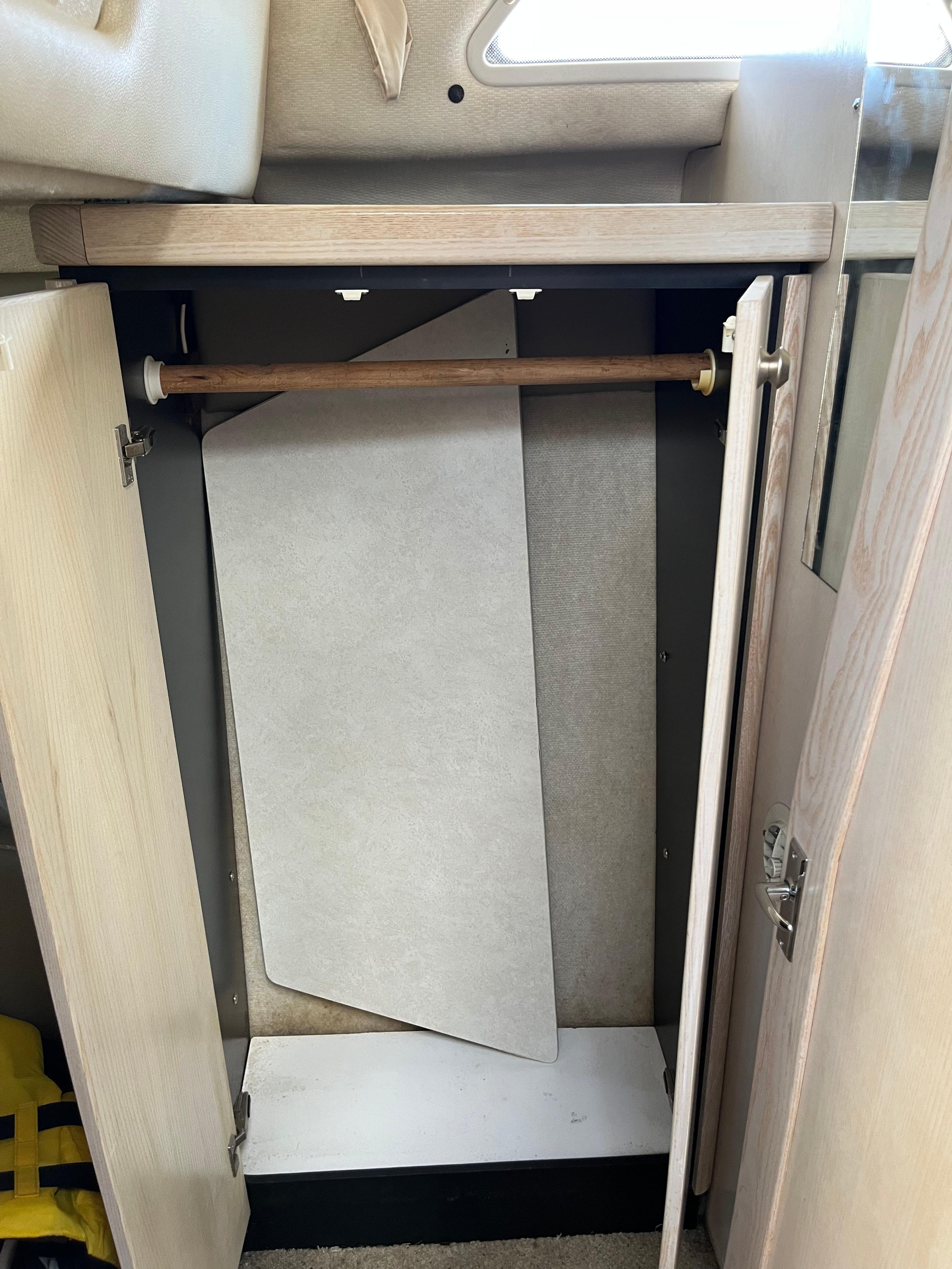 Slide: The Image of Open closet in a 1996 Bayliner 32 Avante boat with wooden rod and panel. - 25