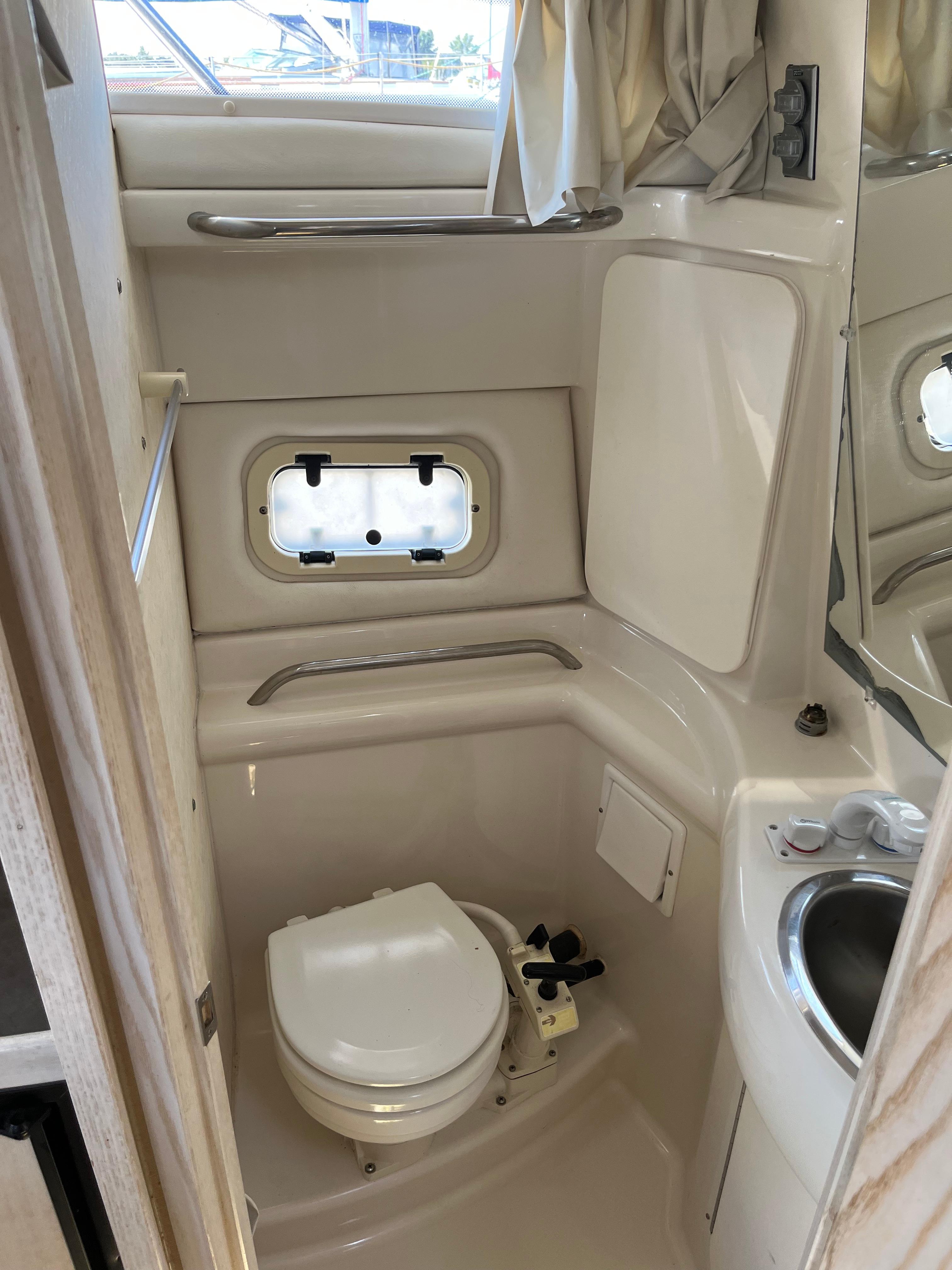 Slide: The Image of Compact bathroom in a 1996 Bayliner 32 Avante boat with toilet, sink, and window. - 33