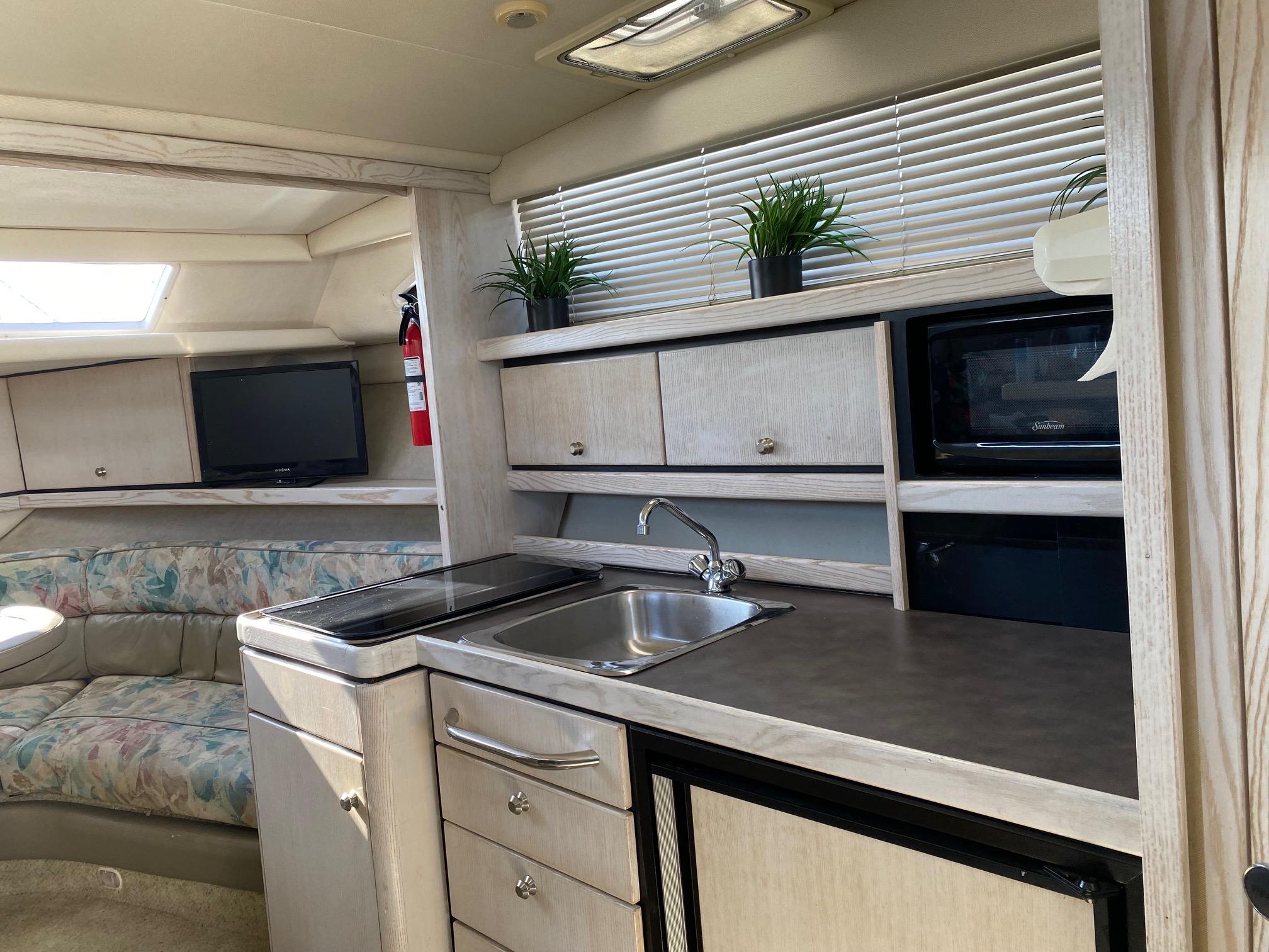 Slide: The Image of Interior of 1996 Bayliner 32 Avante with kitchenette, seating area, TV, and microwave. - 42