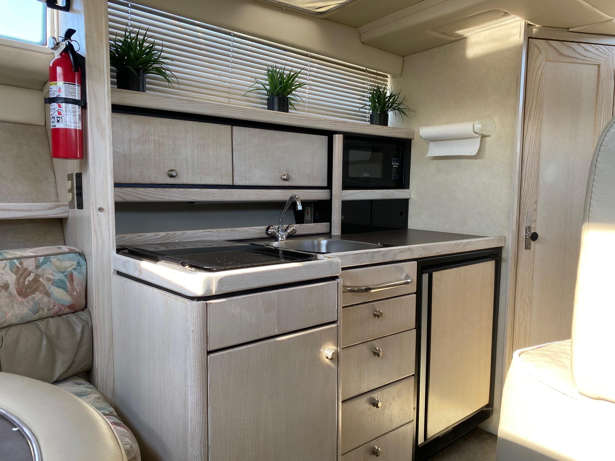 Slide: The Image of Compact kitchen area in a 1996 Bayliner 32 Avante boat with sink, stove, and storage. - 43