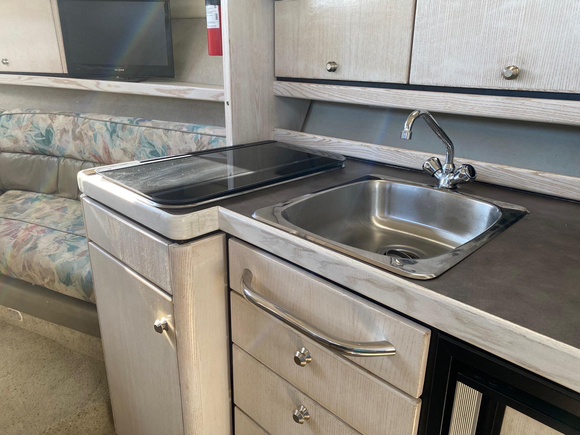 Slide: The Image of 1996 Bayliner 32 Avante kitchen area with sink, stove, and cabinets. - 46
