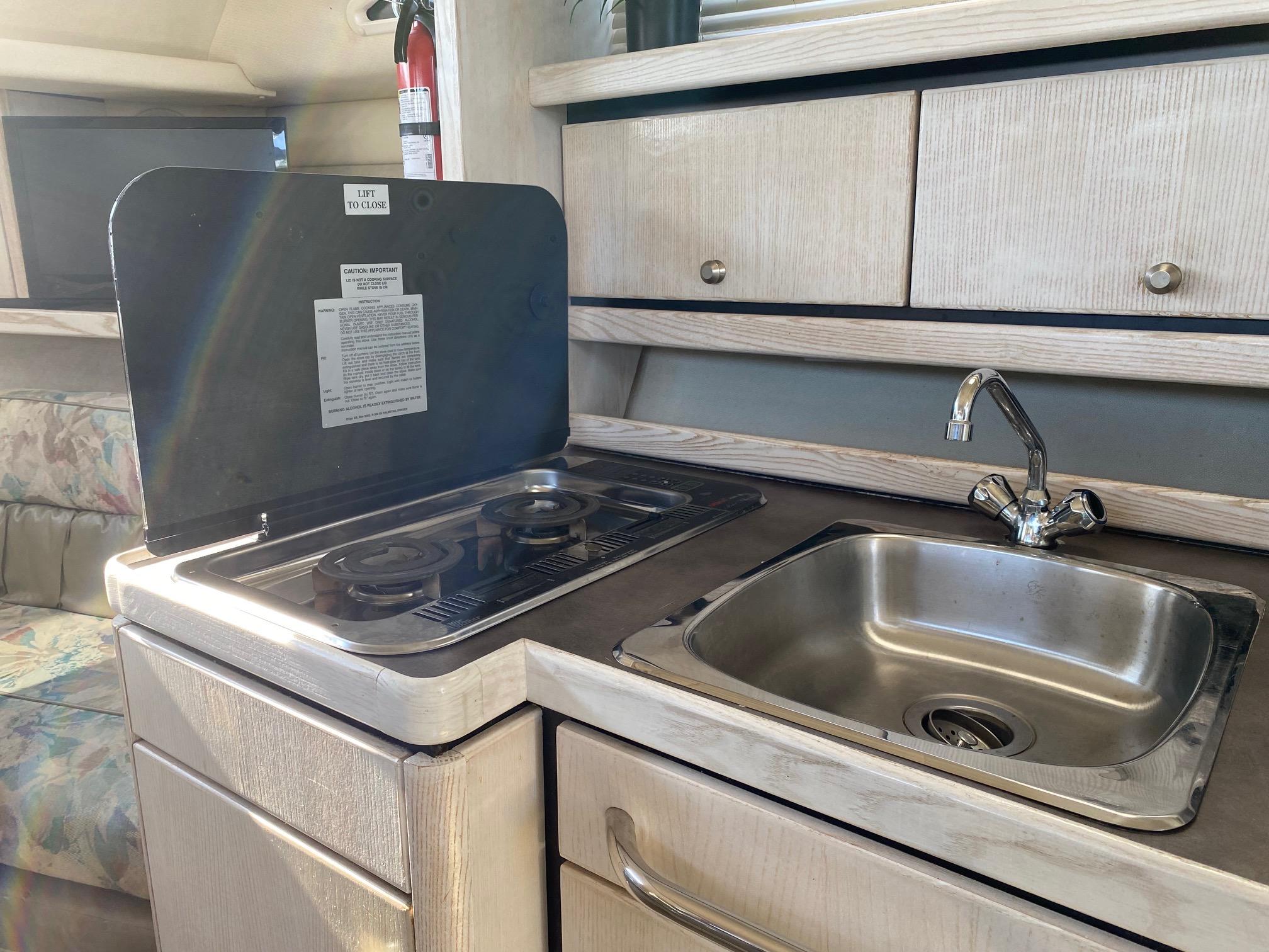 Slide: The Image of 1996 Bayliner 32 Avante boat kitchen with stove, sink, and storage cabinets. - 47