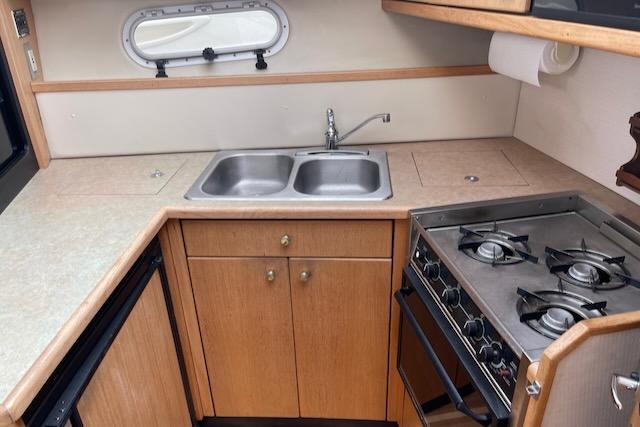 Slide: The Image of 2000 Bayliner 3388 boat kitchen with stove, sink, and cabinets. - 18