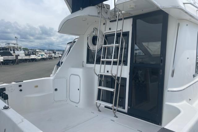 Slide: The Image of 2000 Bayliner 3388 boat stern with ladder and docked boats in background. - 2