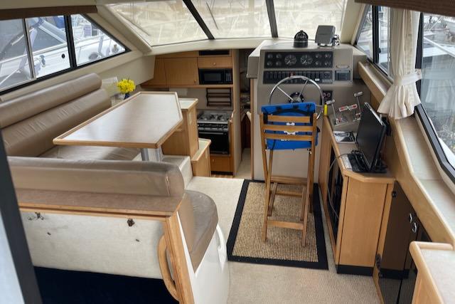 Slide: The Image of Interior of a 2000 Bayliner 3388 boat with helm, seating, and dining area. - 8