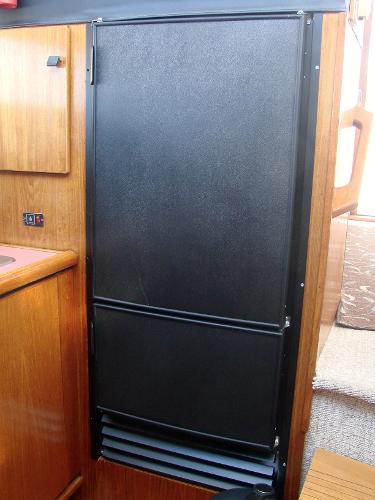 Slide: The Image of 1987 Bayliner 3888 Motoryacht interior with black refrigerator and wooden cabinetry. - 5