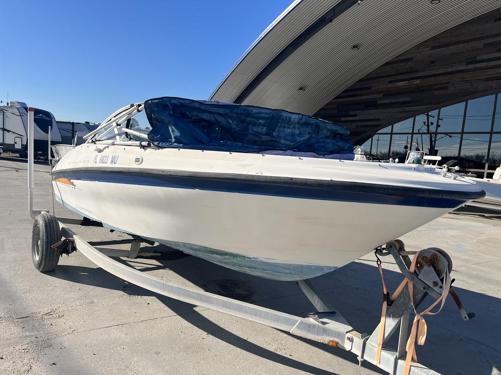 Slide: The Image of 2004 Bayliner 175 boat on trailer, parked outdoors near a modern building. - 7