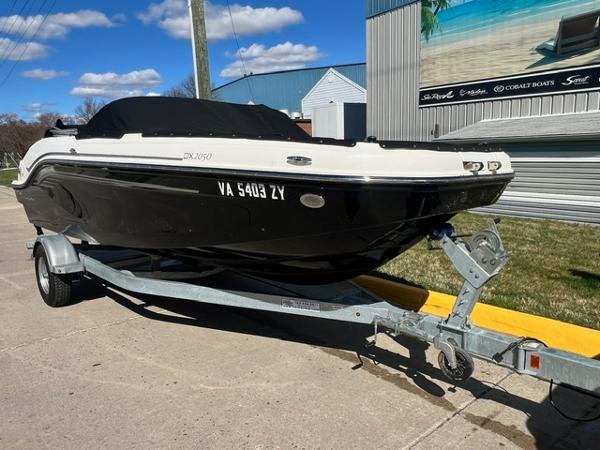 Slide: The Image of 2023 Bayliner DX 2050 boat on a trailer outside a dealership. - 2