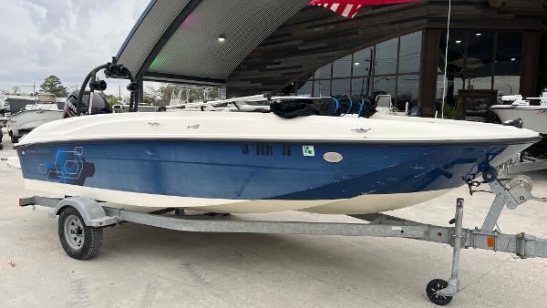 Slide: The Image of 2017 Bayliner Element E 18 boat on trailer, blue and white design, parked outdoors. - 2