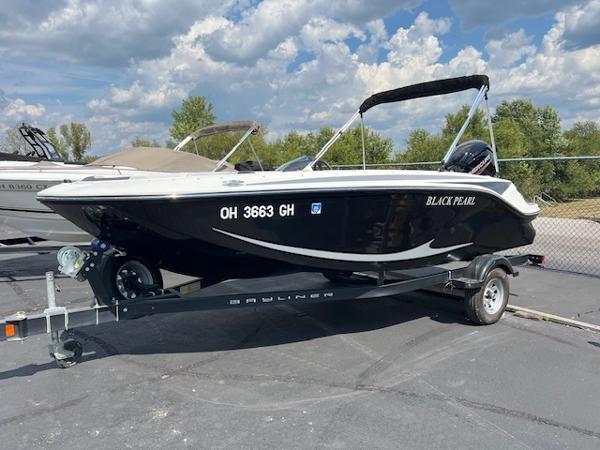 Slide: The Image of 2022 Bayliner Element M17 boat on trailer, black hull, parked outdoors. - 1