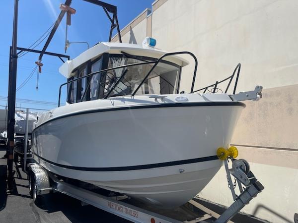 Slide: The Image of 2024 Bayliner Trophy 23 Pilothouse boat on a trailer in a marina. - 1