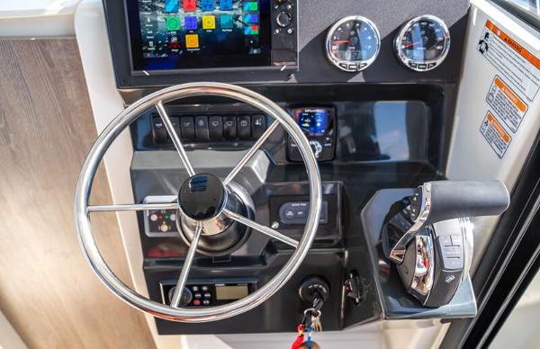 Slide: The Image of 2024 Bayliner Trophy 23 Pilothouse helm with steering wheel, controls, and navigation display. - 15