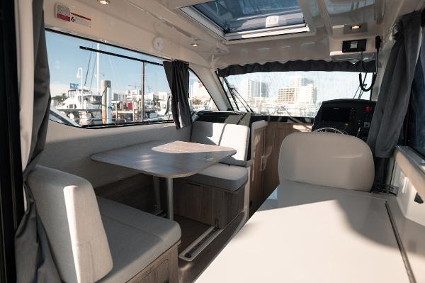 Slide: The Image of 2024 Bayliner Trophy T29EX interior with dining area and helm, featuring modern design and large windows. - 5