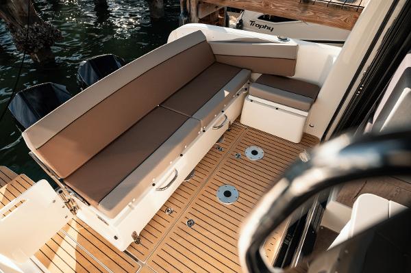 Slide: The Image of 2024 Bayliner Trophy T29EX boat interior with cushioned seating and teak flooring. - 7