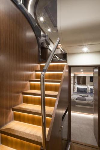 Slide: The Image of Interior of 2024 Belize 66 Sedan yacht with illuminated wooden staircase. - 13