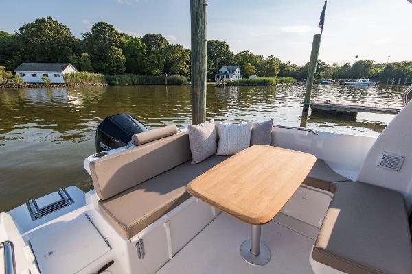 Slide: The Image of 2025 Beneteau Antares 7 boat with outdoor seating and table by a serene lake. - 5