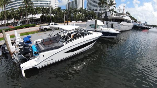 Slide: The Image of 2020 Beneteau Flyer 32 docked in a marina with palm trees and buildings. - 2