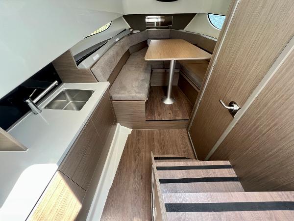 Slide: The Image of 2024 Beneteau Flyer 9 SUNdeck interior with kitchenette, dining area, and wooden finishes. - 15