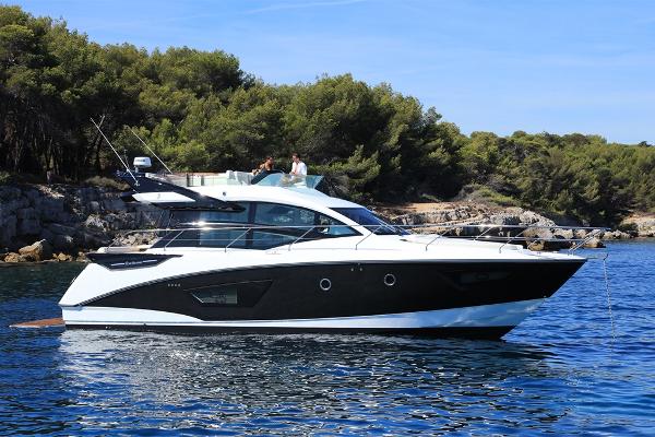 Slide: The Image of 2021 Beneteau Gran Turismo 50 Sportfly yacht cruising near a forested coastline. - 4