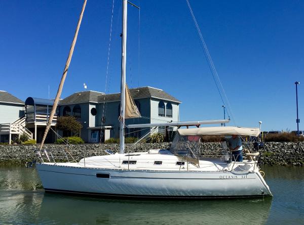Slide: The Image of 2000 Beneteau Oceanis 321 sailboat docked near waterfront homes under clear blue sky. - 1
