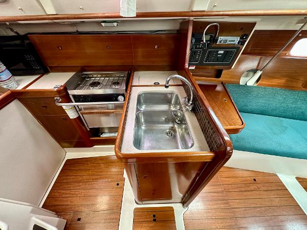 Slide: The Image of Interior of 2000 Beneteau Oceanis 321 yacht, featuring a compact kitchen with sink and stove. - 11