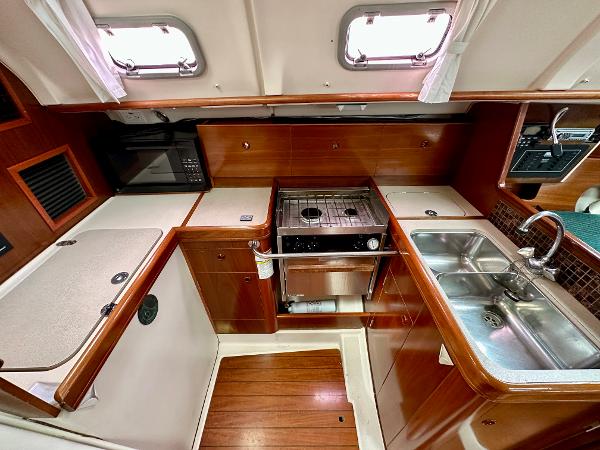 Slide: The Image of Beneteau Oceanis 321 yacht kitchen, featuring stove, sink, and wooden cabinetry, year 2000 model. - 13
