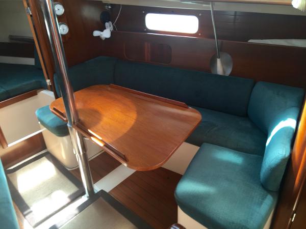 Slide: The Image of Interior of 2000 Beneteau Oceanis 321 sailboat with wooden table and teal seating. - 16