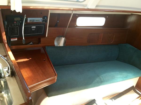Slide: The Image of Interior of 2000 Beneteau Oceanis 321 sailboat with wooden table and teal sofa. - 17