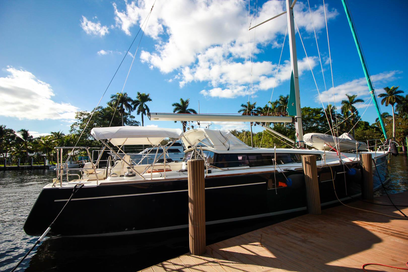 Slide: The Image of 2015 Beneteau Sense 55 sailboat docked at a marina under a clear blue sky. - 1