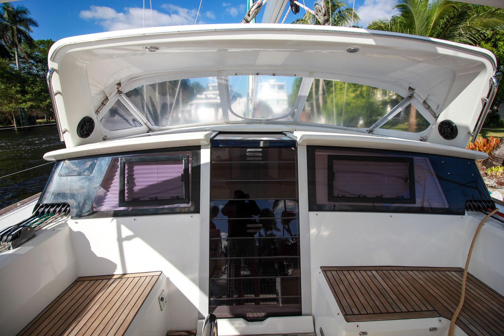 Slide: The Image of Cockpit view of 2015 Beneteau Sense 55 sailboat with teak seating and clear canopy. - 12