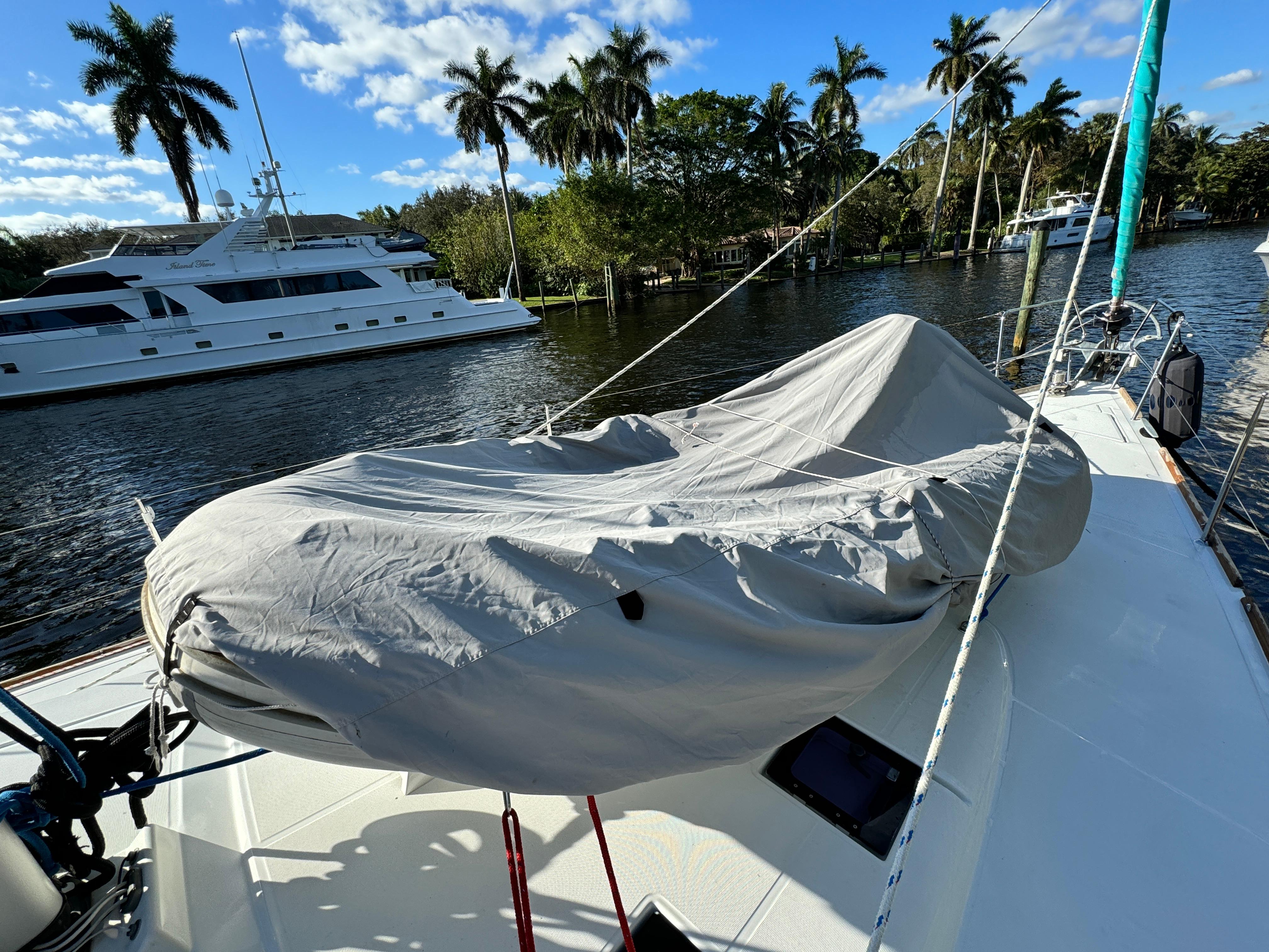 Slide: The Image of Beneteau Sense 55 sailboat deck, covered dinghy, docked near palm trees and yachts, 2015 model. - 16