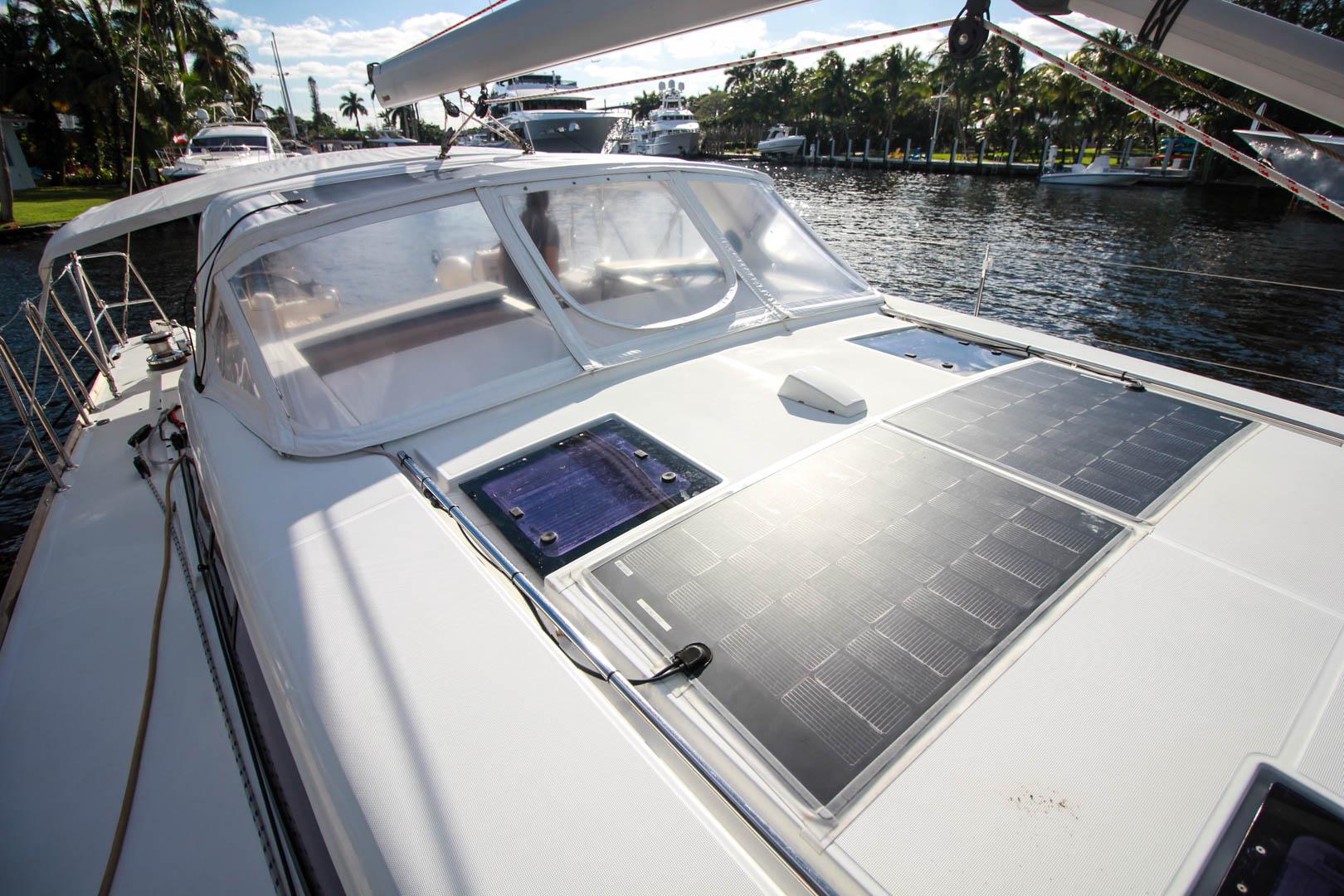 Slide: The Image of 2015 Beneteau Sense 55 sailboat with solar panels on deck, docked by the water. - 23