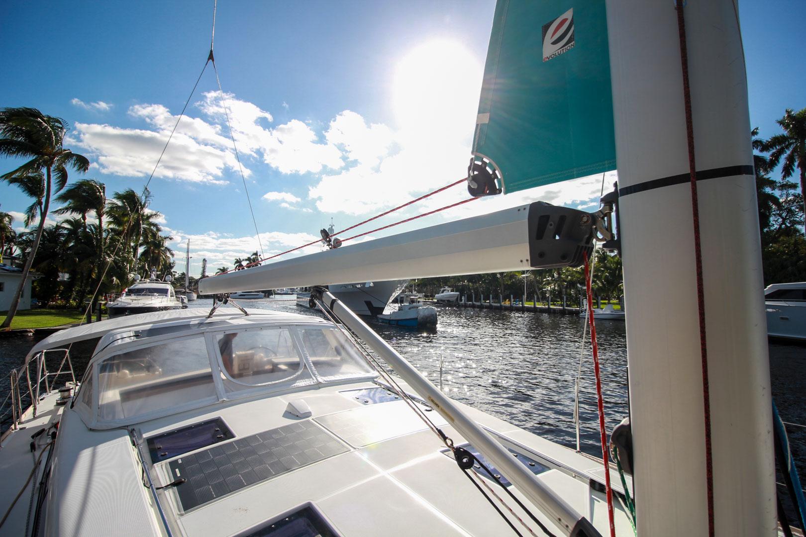 Slide: The Image of 2015 Beneteau Sense 55 sailboat on a sunny day, docked near palm trees. - 25