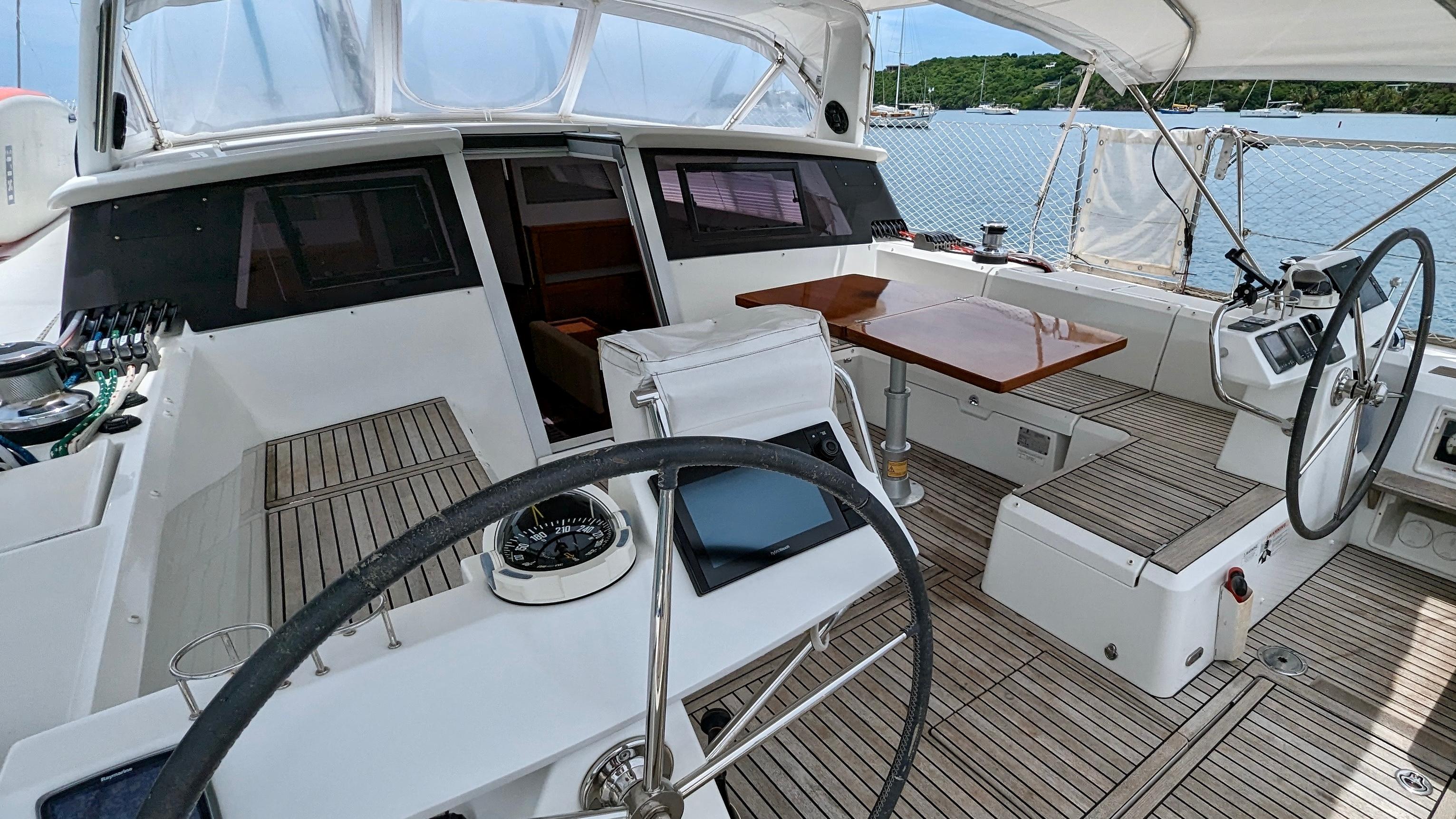 Slide: The Image of Cockpit of 2015 Beneteau Sense 55 sailboat with dual steering wheels and wooden table. - 28
