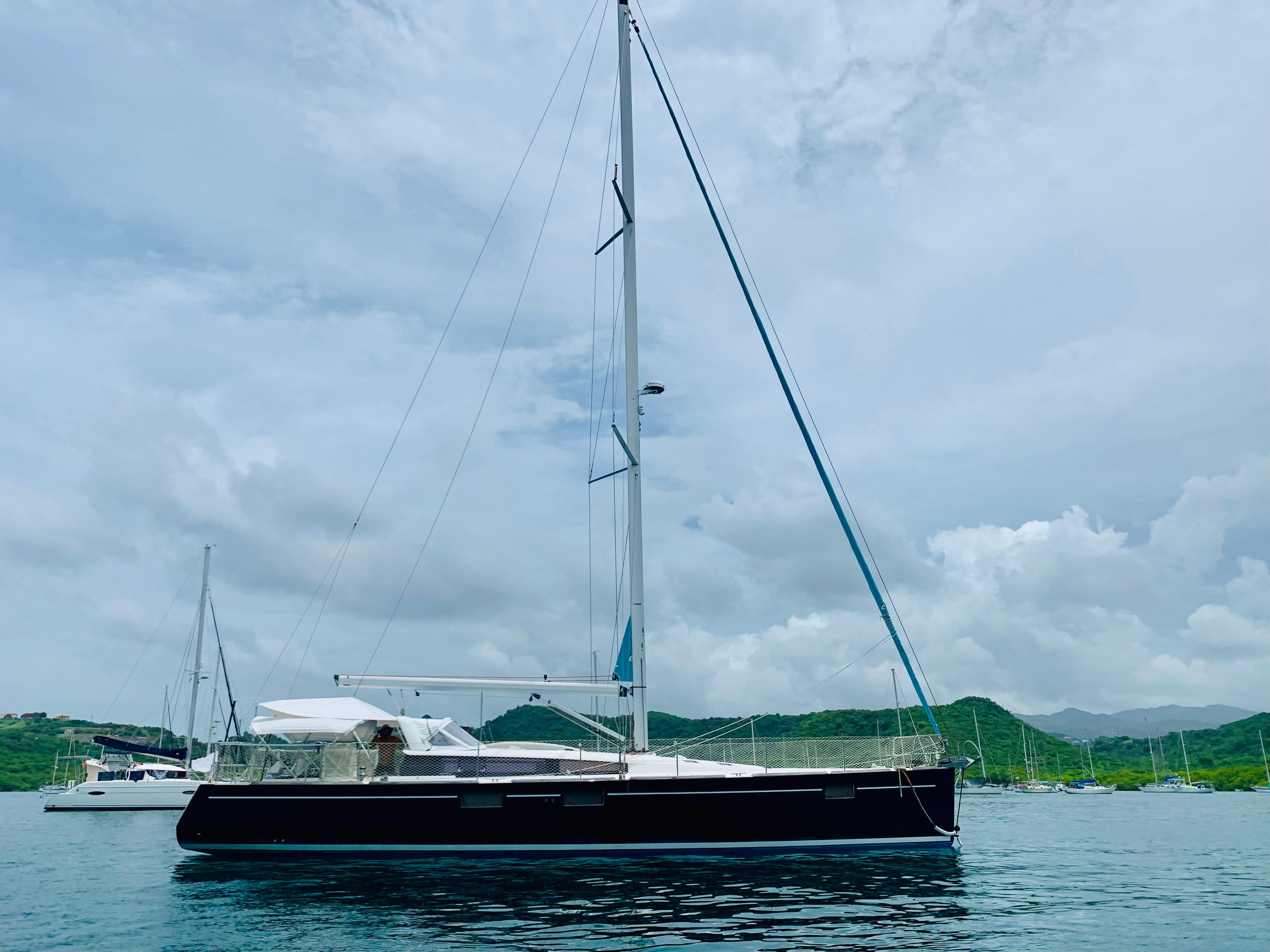 Slide: The Image of 2015 Beneteau Sense 55 sailboat anchored in a scenic bay. - 3