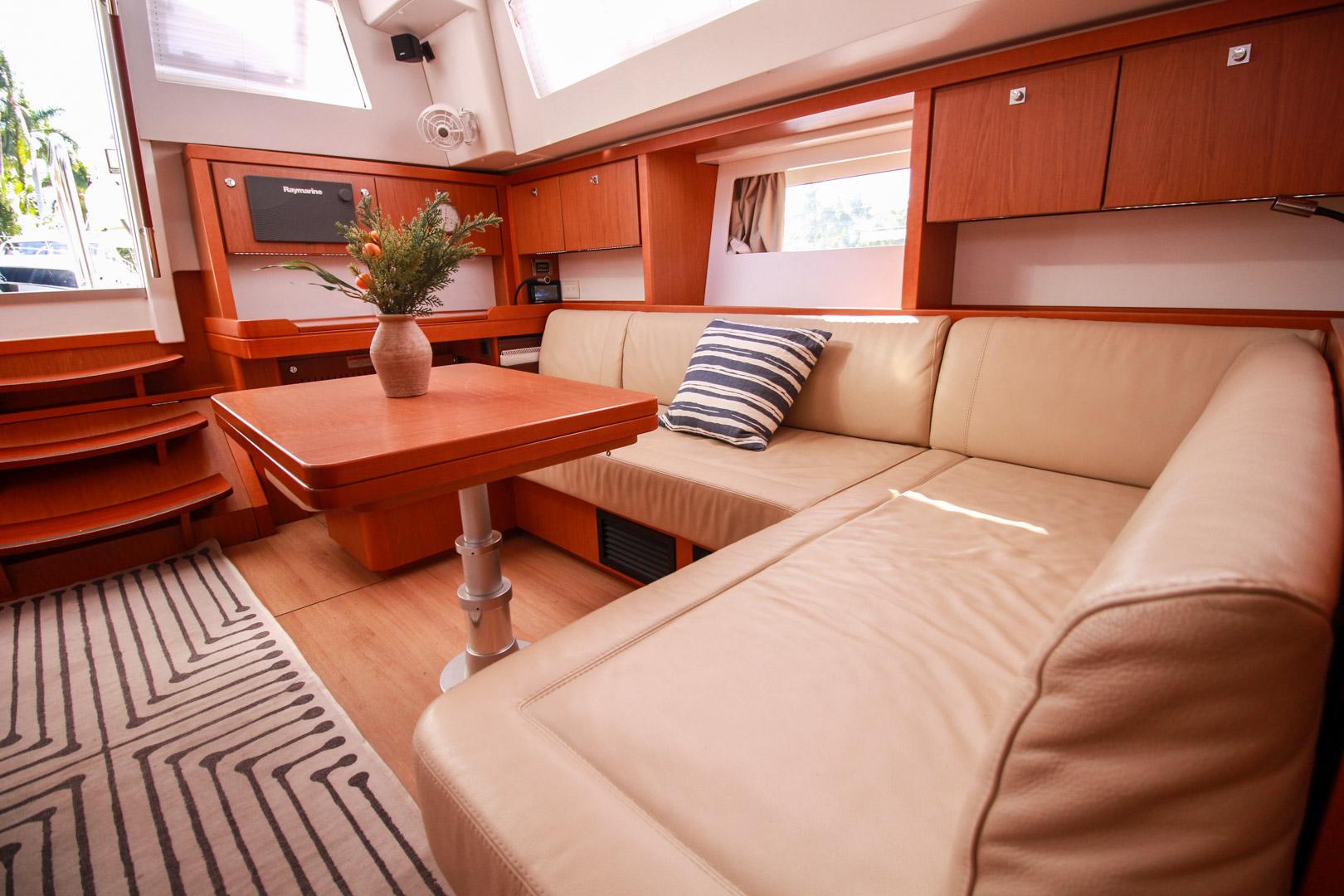 Slide: The Image of Interior of 2015 Beneteau Sense 55 yacht with beige leather seating and wooden table. - 34