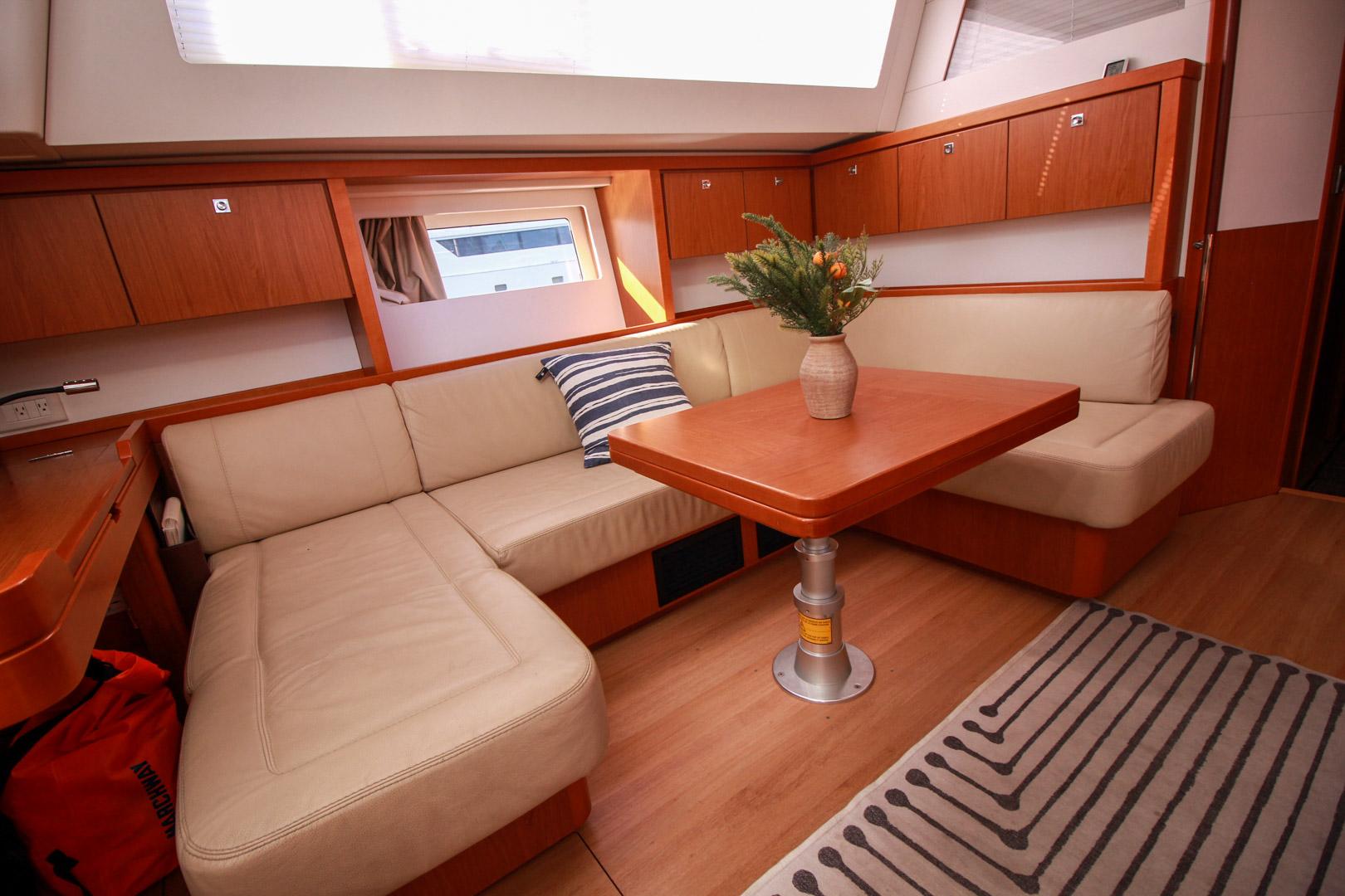 Slide: The Image of Interior of 2015 Beneteau Sense 55 yacht with beige seating and wooden table. - 35