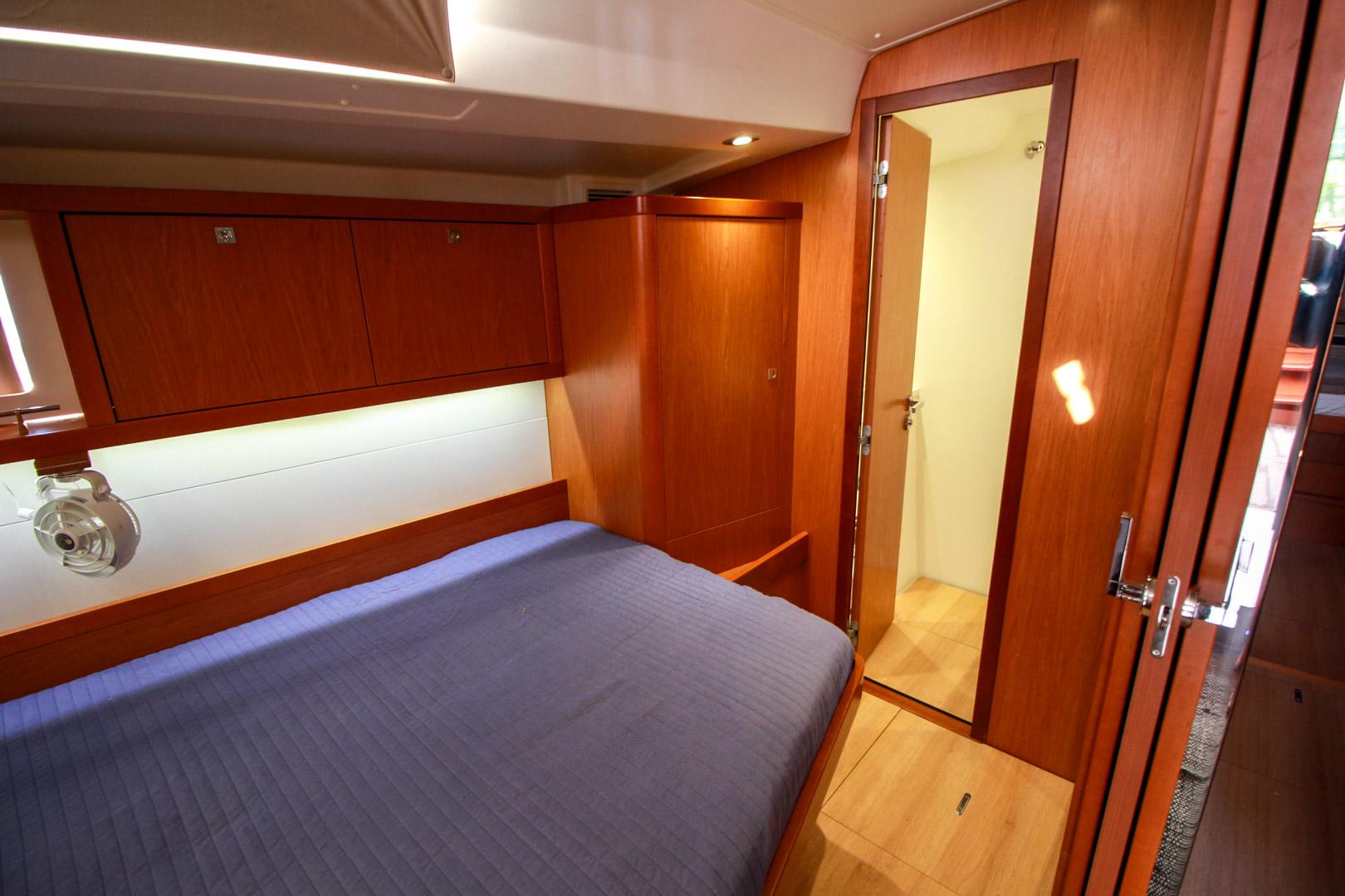 Slide: The Image of 2015 Beneteau Sense 55 yacht cabin with wooden interior and blue bedding. - 44