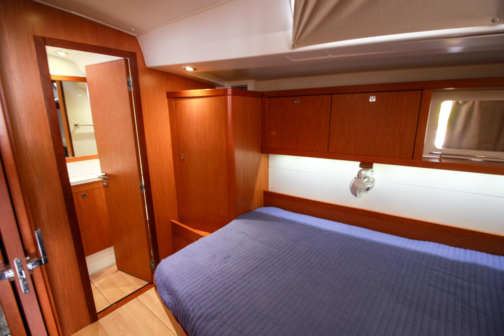 Slide: The Image of Interior cabin of 2015 Beneteau Sense 55 yacht with wooden finish and blue bedding. - 45