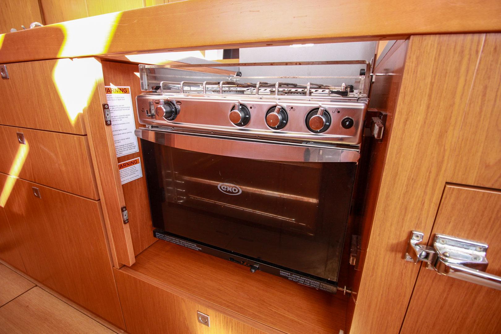 Slide: The Image of Beneteau Sense 55 2015 yacht kitchen with built-in stainless steel oven and wooden cabinetry. - 49