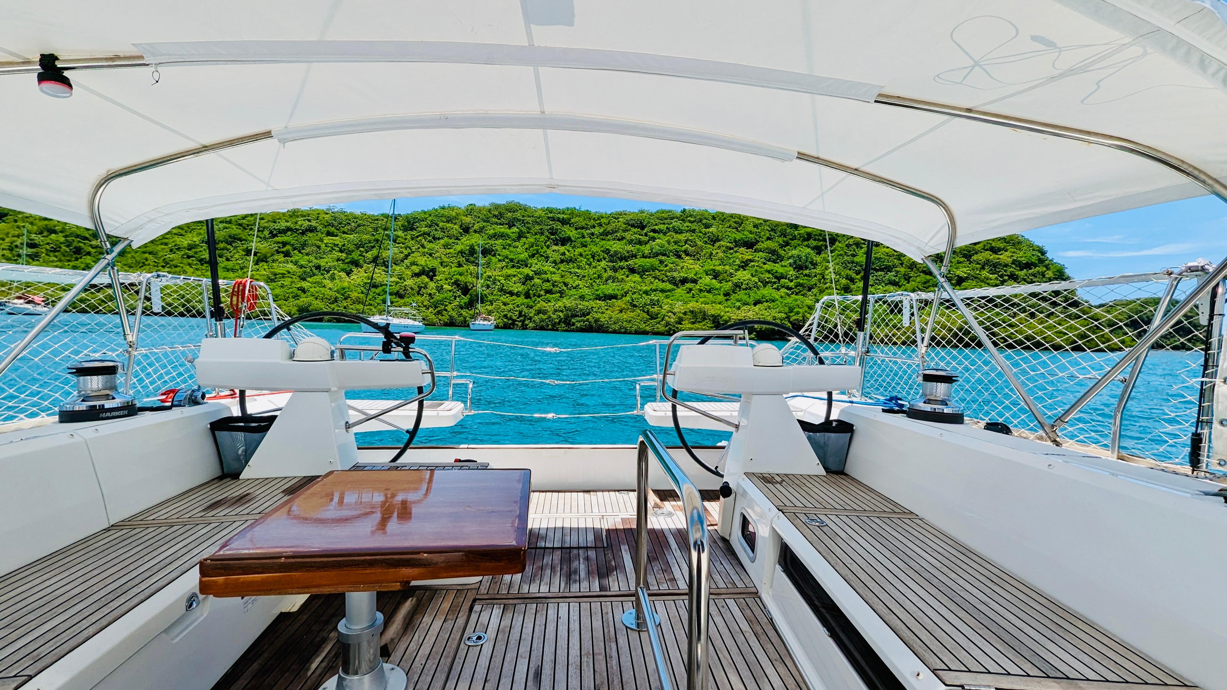 Slide: The Image of Cockpit view of 2015 Beneteau Sense 55 sailboat with scenic ocean and island backdrop. - 7