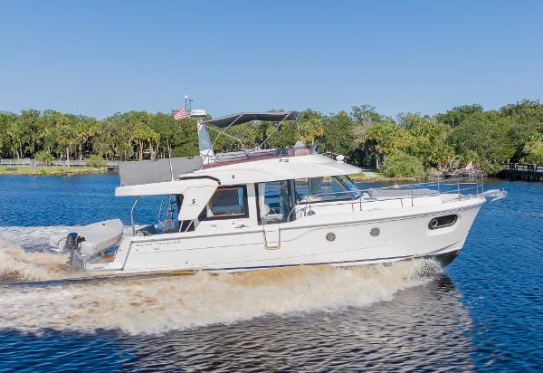 Slide: The Image of 2021 Beneteau Swift Trawler 41 cruising on a sunny day, surrounded by lush greenery. - 1