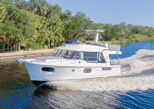 Slide: The Image of 2021 Beneteau Swift Trawler 41 cruising on a scenic river with lush greenery. - 2