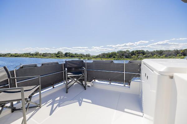 Slide: The Image of 2021 Beneteau Swift Trawler 41 deck with chairs, overlooking serene water and lush greenery. - 44
