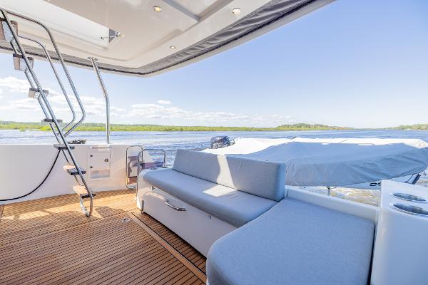 Slide: The Image of 2021 Beneteau Swift Trawler 41 deck with seating, overlooking serene water and distant shoreline. - 47