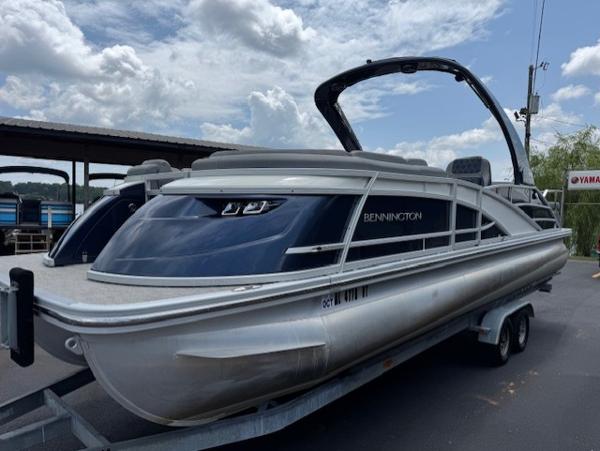 Slide: The Image of 2023 Bennington 25 QSBA pontoon boat on trailer under cloudy sky. - 1