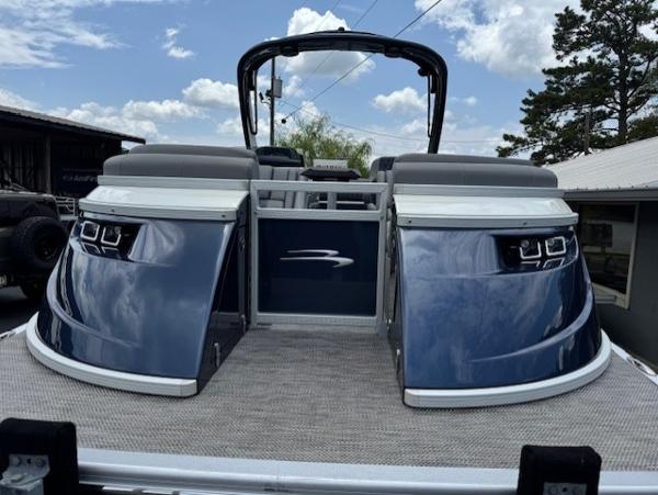 Slide: The Image of 2023 Bennington 25 QSBA pontoon boat, rear view, blue and white design, under a partly cloudy sky. - 2