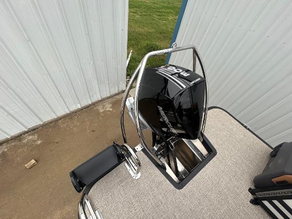 Slide: The Image of 2025 Bennington M26 boat with a powerful outboard motor, docked near a metal building. - 10