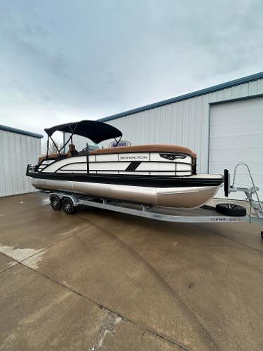 Slide: The Image of 2025 Bennington M26 pontoon boat on trailer, parked outside a warehouse. - 3