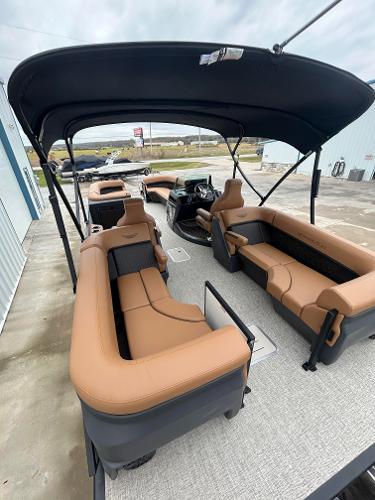 Slide: The Image of 2025 Bennington M26 boat interior with tan seating and canopy, docked outdoors. - 9